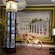A museum display featuring a bicyle, a tower clock, a video display and a large mural of 2 neoclassical buildings